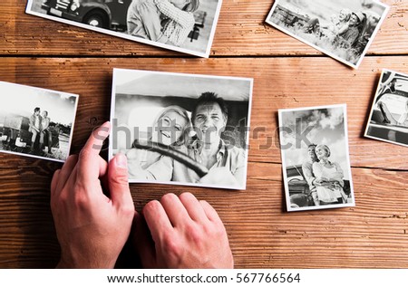 Hands holding pictures of senior couple. Studio shot, wooden bac