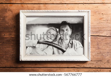 Photo of seniors in picture frame laid on wooden background.