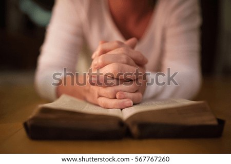 Unrecognizable woman praying, hands clasped together on her Bibl Royalty-Free Stock Photo #567767260