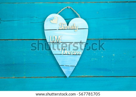 Blank broken heart shaped sign with the words Family, Love and Dream hanging on rustic antique teal blue wood background; Valentines Day, Mothers Day and love concept with painted copy space