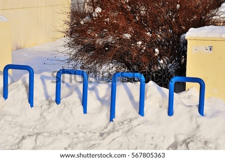 empty bicycle parking rack painted in blue on wintertime under snow