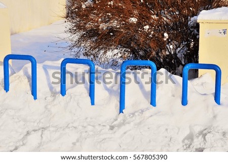 empty bicycle parking rack painted in blue on wintertime under snow