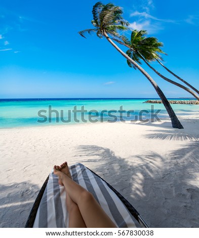 Woman on sunbed under palm tree at tropical island