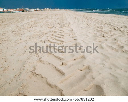 Tyre tracks and footprints in the sand.