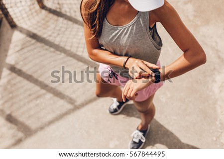 Top view shot of young woman checking fitness progress on her smart watch. Female runner using fitness app to monitor workout performance. Royalty-Free Stock Photo #567844495