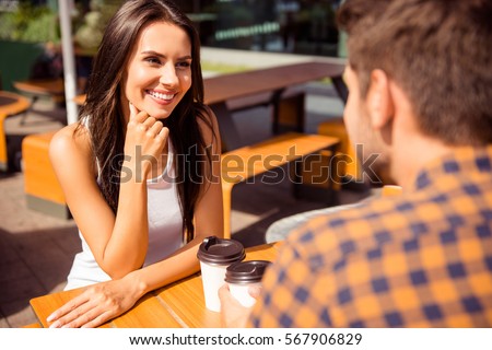 Smiling couple in love talking in outdoor cafe and drinking coffee. Royalty-Free Stock Photo #567906829