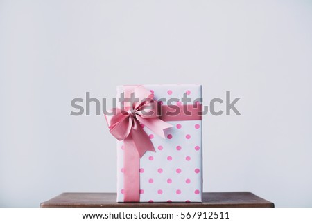 Beautiful gift box with a pink bow on a wooden table.