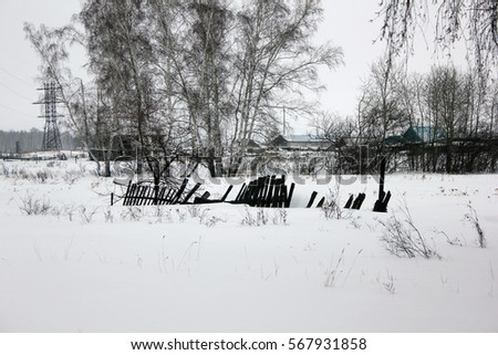 Snow-covered old village rotten fence 