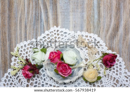 Shabby artificial Pink white beige flowers and lace decor on beautiful wooden table desk with shadow background, free copy space for text on paper note. Shabby chic interior office holiday decorations