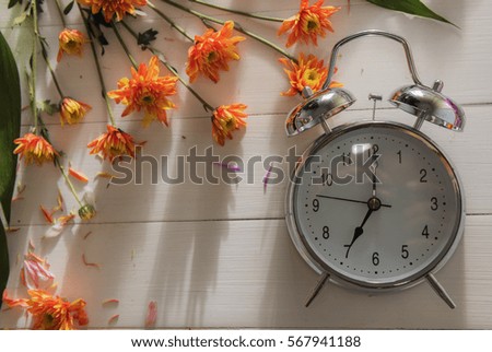 Flower vintage silver alarm clock with shadow of wooden battens on white wooden table background on Valentine's Day times with copy space.
