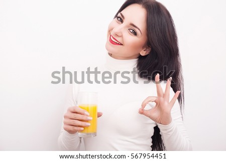 Portrait of a beautiful young woman with a glass of juice and orange, on white background.