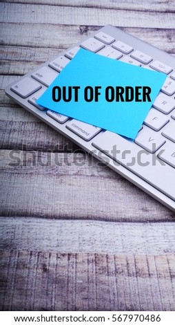 OUT OF ORDER text on Colourful sticky note and keyboard on wooden background. Business concept.