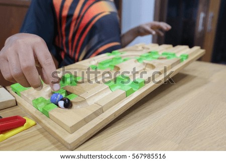 Close up photography of right hand of kid play wooden and marble toys at home in the night time, soft focus