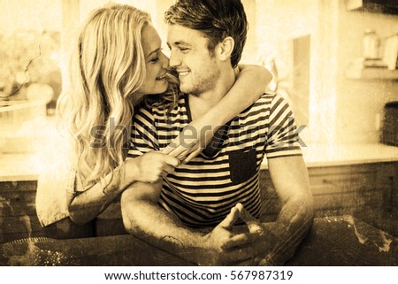 Grey background against couple embracing in kitchen