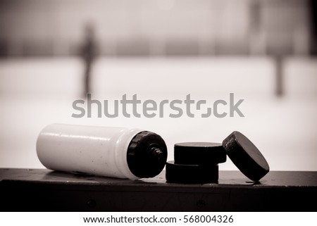 Black and white Water bottle with puck on the boards in a hockey arena