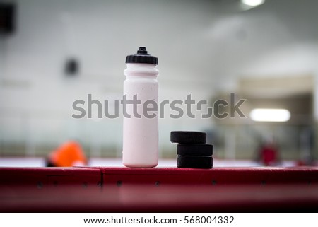 Water bottle with puck on the boards in a hockey arena