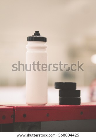 Vintage Water bottle with puck on the boards in a hockey arena