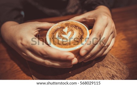 Both hands with a heart symbol holding a hot coffee cup in vintage style.
