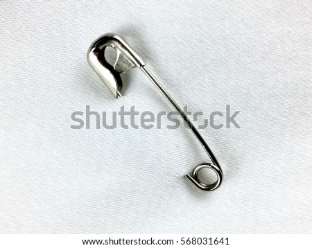 Safety pin on white fabric Royalty-Free Stock Photo #568031641