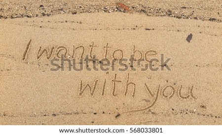 Handwriting words "I want to be with you." on sand of beach