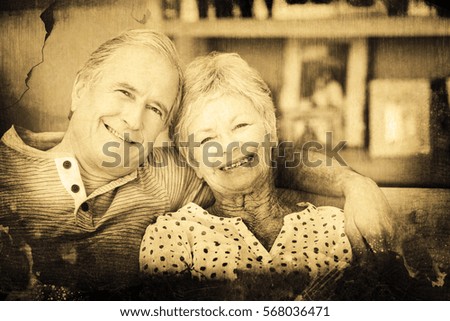 Grey background against portrait of senior couple sitting on sofa