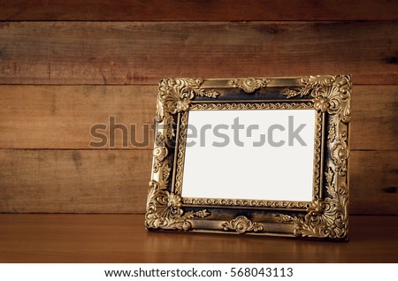 Vintage gold photo frame on wooden table over wooden background