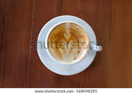 Empty cup of hot latte art with heart foam picture on surface serve in white cup on the wooden table.