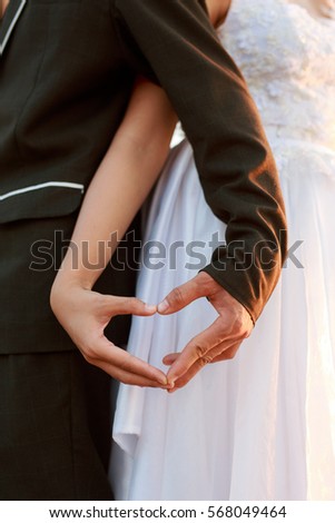 close up groom and bride hands in shape of love heart.