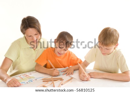 young mother sitting at the table and draws with his sons
