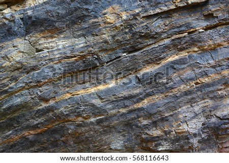 Background on the basis of the texture of rock. Black and red stone with sloping layers and cracks