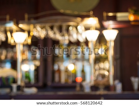 Classic bar counter with bottles in blurred background. Interior of pub or bar at night. Luxury restaurant
