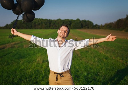 satisfied man holding black balloons