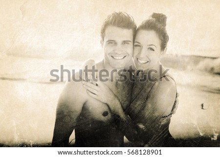 Grey background against portrait of happy couple embracing at beach