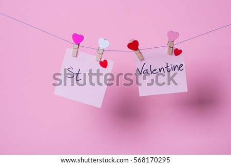 Paper sheets on thread with heart shaped clothespin on rose background