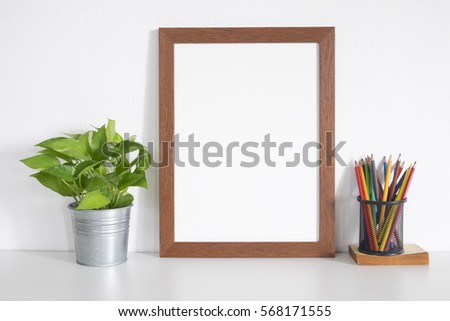 mock up wooden frame with  crayon and plant pot on table