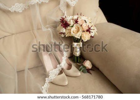 Bridal shoes and wedding bouquet on armchair.
