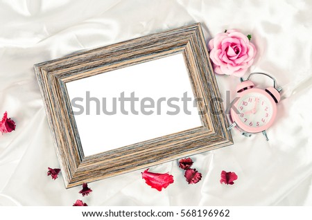 Blank wooden photo frame and pink alarm clock with rose. Saved clipping path.