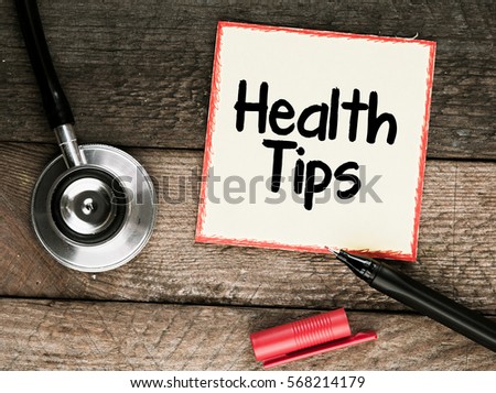 Health tips. Medicine concept / Paper sticker with inscription, stethoscope, pen on wooden table.