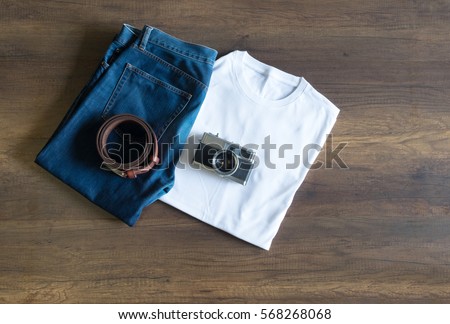 Top view of clothing and vintage camera laying on the wooden plate