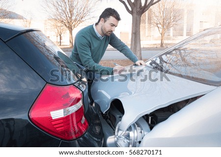 Man writing a car insurance claim after a car crash