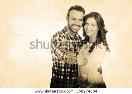 Happy young couple putting thumbs up against grey background