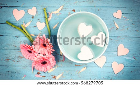 beautiful lovely pink Gerbera daisy with hearts in a bowl on rustic background             