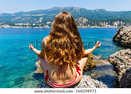 Young woman sitting in lotus position on the beach