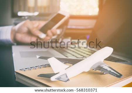 Business man is making call in office for global communication. A man holding mobile phone with Airplane on for ground for Business travel communication concept. Royalty-Free Stock Photo #568310371