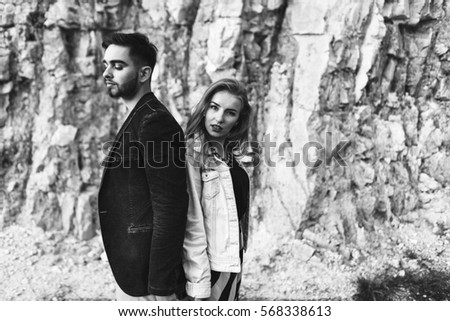 handsome guy with a blond girl walking and posing near the rock slopes. tender love story. holding hands in hands
