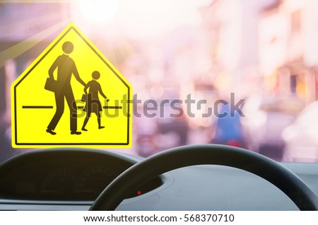 School zone warning sign and inside car view ,steering wheel on blur traffic road with colorful bokeh light abstract background. Copy space of transportation and travel concept. Vintage tone color.