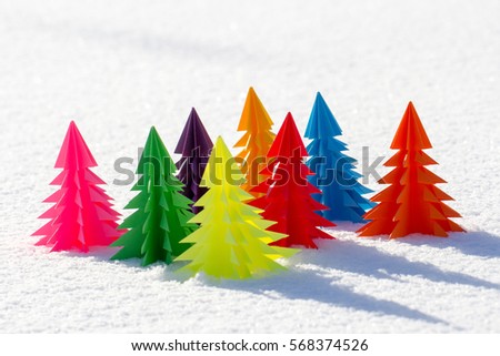 Trees of different colors of paper in the snow.