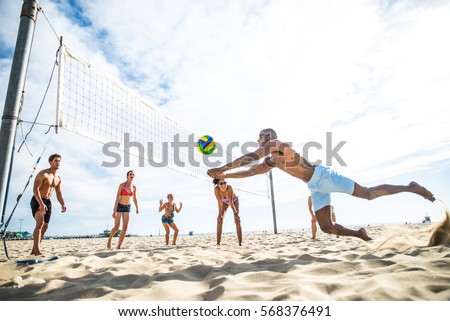 Group of friends playing beach volley - Multi-ethic group of people having fun on the beach Royalty-Free Stock Photo #568376491