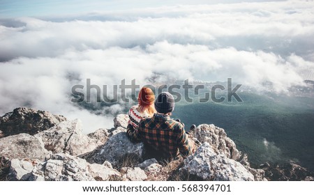 Couple Man and Woman sitting on cliff enjoying mountains and clouds landscape Love and Travel happy emotions Lifestyle concept. Young family traveling active adventure vacations Royalty-Free Stock Photo #568394701