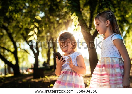 Beautiful girls having fun in the park with their mobile phone.